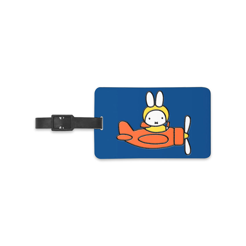 Miffy® bagagebricka i mörkblå silikon med reliefmotiv av Miffy i orange propellerflygplan och gul pilotmössa.