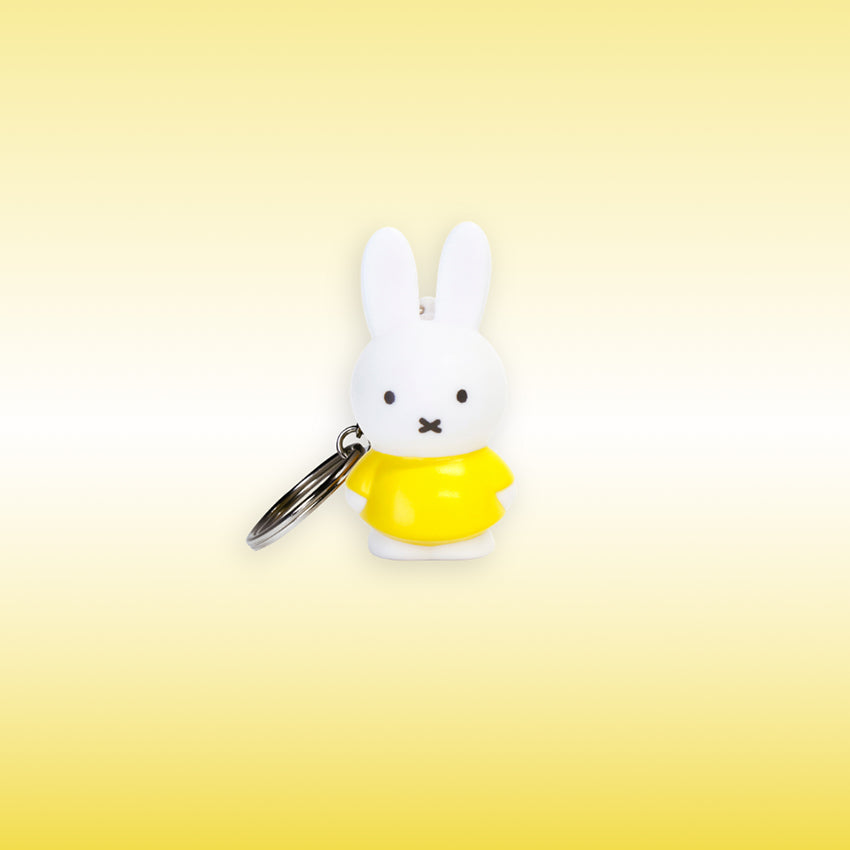 Miffy® 3D-nyckelring i matt vit plast med Miffy i gult och metallkedja med nyckelring.