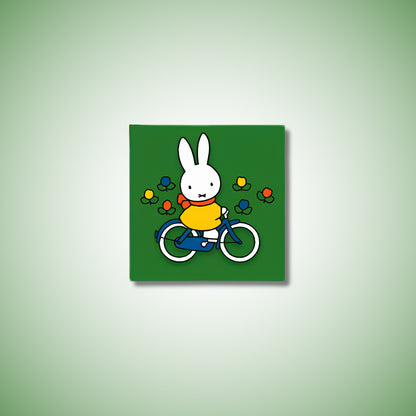 Miffy® kylskåpsmagnet i två lager MDF med mörkgrön bakgrund, små tulpaner och utfräst motiv av Miffy på cykel.