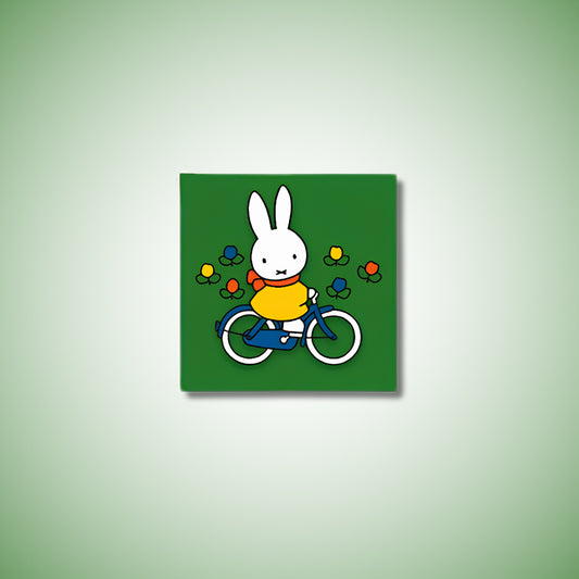 Miffy® kylskåpsmagnet i två lager MDF med mörkgrön bakgrund, små tulpaner och utfräst motiv av Miffy på cykel.