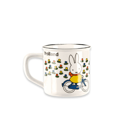 Miffy® retro mugg i offwhite keramik med svart kant och motiv av Miffy på cykel genom ett holländskt tulpanfält med orange-röd halsduk.