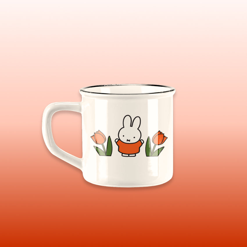 Miffy® retro mugg i offwhite keramik med svart kant, Miffy i orange kläder och orange-röda tulpaner på båda sidor av muggen.