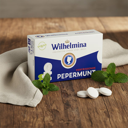 en ask med Wilhelmina-pepparmint på ett robust träbord med några myntablad